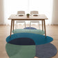 Dining table with chairs on a wooden floor featuring multicolored circular rugs.