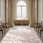 Luxurious room with a pink and white patterned rug, wooden chairs, and a large window.
