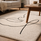 Beige rug with black leaf design in a living room setting