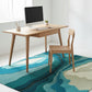 Modern office setup with a wooden desk, chair, and computer on a colorful rug.