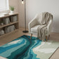 Living room with a blue and green patterned rug, white armchair, and bookshelf.
