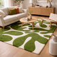 Living room with a green and white abstract rug, beige sofa, and wooden coffee table.