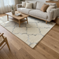 Living room with a beige sofa, wooden coffee table, and patterned rug on wooden floor.