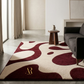 Living room with a patterned red and beige rug, gray sofa, and wooden side table.