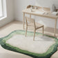 Green and white rug on a wooden floor with a desk and chair in the background.