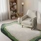 Living room with a green and white rug, beige armchair, and bookshelf.