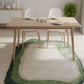 Dining table with chairs on a green and beige area rug in a room.