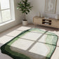 Green and white patterned rug on a wooden floor with a plant and cabinet in the background.