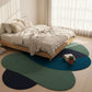 Colorful round rug on a wooden floor in a bedroom with a bed and window.
