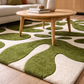 Wooden coffee table on a green and white patterned rug in a living room setting.