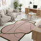 Modern living room with a pink and green rug, gray sofa, and wooden desk.