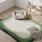 Green and white rug on a wooden floor with a pet bed and blanket in a room.
