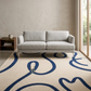 Gray sofa in a room with a blue and beige patterned rug.
