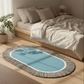 Blue oval rug with black stripes on a wooden floor in a bedroom setting.