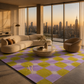 A modern living room with a large area rug featuring a purple and yellow-green checkered pattern with white starburst accents. The rug is styled in a luxury apartment setting with a curved cream boucle sofa, a matching accent chair, and a round stone coffee table, all set against a backdrop of large windows showing a city skyline at sunset.