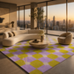 A modern living room with a large patterned area rug in purple and lime green, featuring a curved cream sofa, a round stone coffee table, and a beige accent chair, set against large floor-to-ceiling windows with a city skyline at sunset.