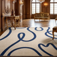 Luxurious room with a patterned rug, ornate furniture, and large windows.