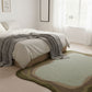 Bedroom with a green and brown rug in front of a bed