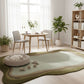 Modern living room with a wavy green rug, white chairs, and a small table.