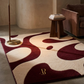 Patterned rug with a gold logo in a room with a side table and chair.