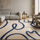Living room with a beige sofa, armchair, and a blue and beige patterned rug.