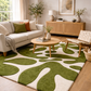 Living room with a green and white patterned rug, beige sofa, wooden coffee table, and decorative items.