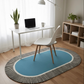 Blue oval rug with black and white stripes in a room with a desk and chair.