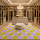 A modern living room with a large patterned area rug in purple and lime green, featuring a curved cream sofa, a round stone coffee table, and a beige accent chair, set against large floor-to-ceiling windows with a city skyline at sunset.

