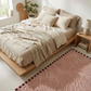 Neatly made bed with beige bedding in a bright bedroom.