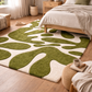 Green and white abstract rug in a bedroom with wooden floor and bed.