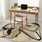 Wooden desk with laptop and chair in a room with a patterned rug.