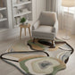 Modern living room with a patterned rug, chair, and bookshelf.