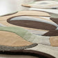 Close-up of a multicolored area rug with abstract design on a light wooden floor.