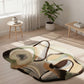 Abstract patterned rug on a wooden floor with a plant and small table in the background.