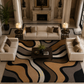 A styled living room featuring a large abstract wavy pattern area rug in beige, brown, black, and gray. The rug is surrounded by a cream-colored sofa, two matching armchairs, a dark wood coffee table, and is set in an elegant room with classical columns and a fireplace.
