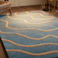 Blue rug with orange wavy lines on a wooden floor