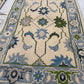Close-up of a patterned rug with blue and green designs on a white background