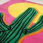Colorful rug with a green cactus design on a pink background