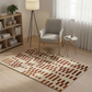 Living room with a patterned rug, chair, bookshelf, and lamp.
