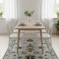 Dining area with a wooden table and chairs on a patterned rug.