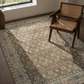 Patterned rug with a chair on a wooden floor near a window