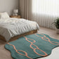 Teal rug with pink patterns on a wooden floor in a bedroom setting.
