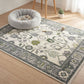 Decorative rug with intricate patterns on a wooden floor, featuring a pet bed and small plants.
