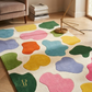 Colorful abstract rug on a wooden floor with books and a lamp in the background.