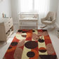 Nursery room with a colorful rug, crib, and rocking chair.