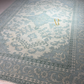 Decorative rug with intricate patterns and a brand logo in the center.