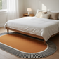 Bedroom with a wooden bed, white bedding, and an orange rug with black stripes.