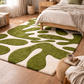 Green and white abstract rug on a wooden floor in a bedroom setting.