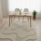 Dining room with a wooden table and chairs on a decorative rug.