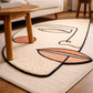Decorative rug with abstract design on a wooden floor in a living room setting.